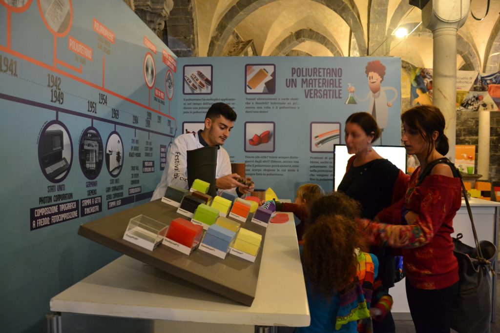 Visitatori intorno al tavolo dei materiali colorati della mostra Prototype