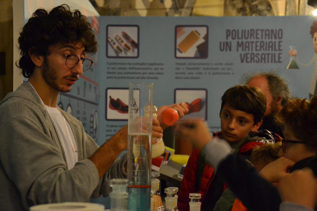 Un animatore mostra un esperimento con bottiglia e imbuto a un gruppo di ragazzi