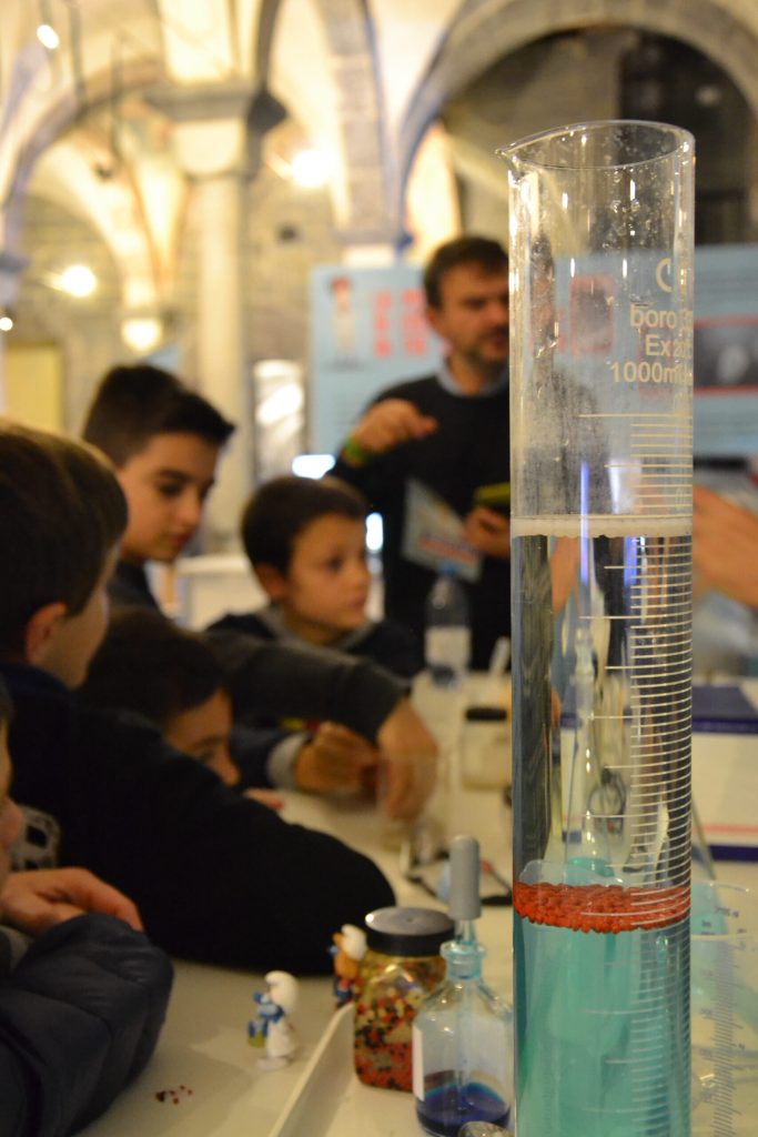 Visitatori davanti alla colonna trasparente riempita di granuli di plastica
