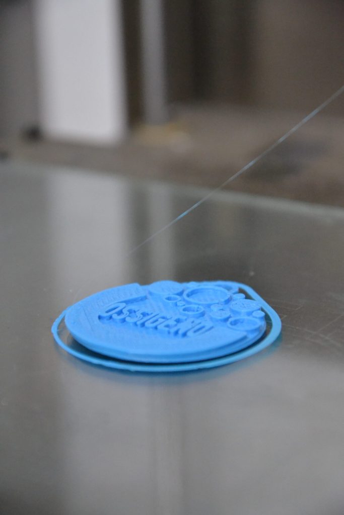 Un coperchio di plastica azzurra stampato in 3D appoggiato sul tavolo