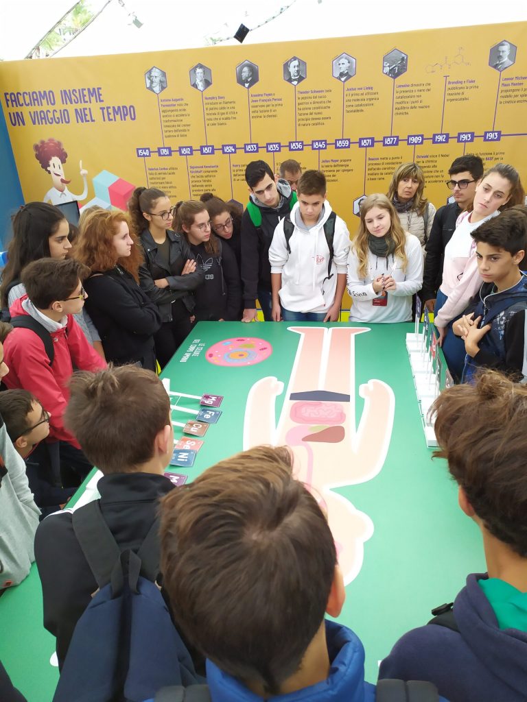 Ragazzi raccolti intorno al tavolo del gioco sugli elementi chimici