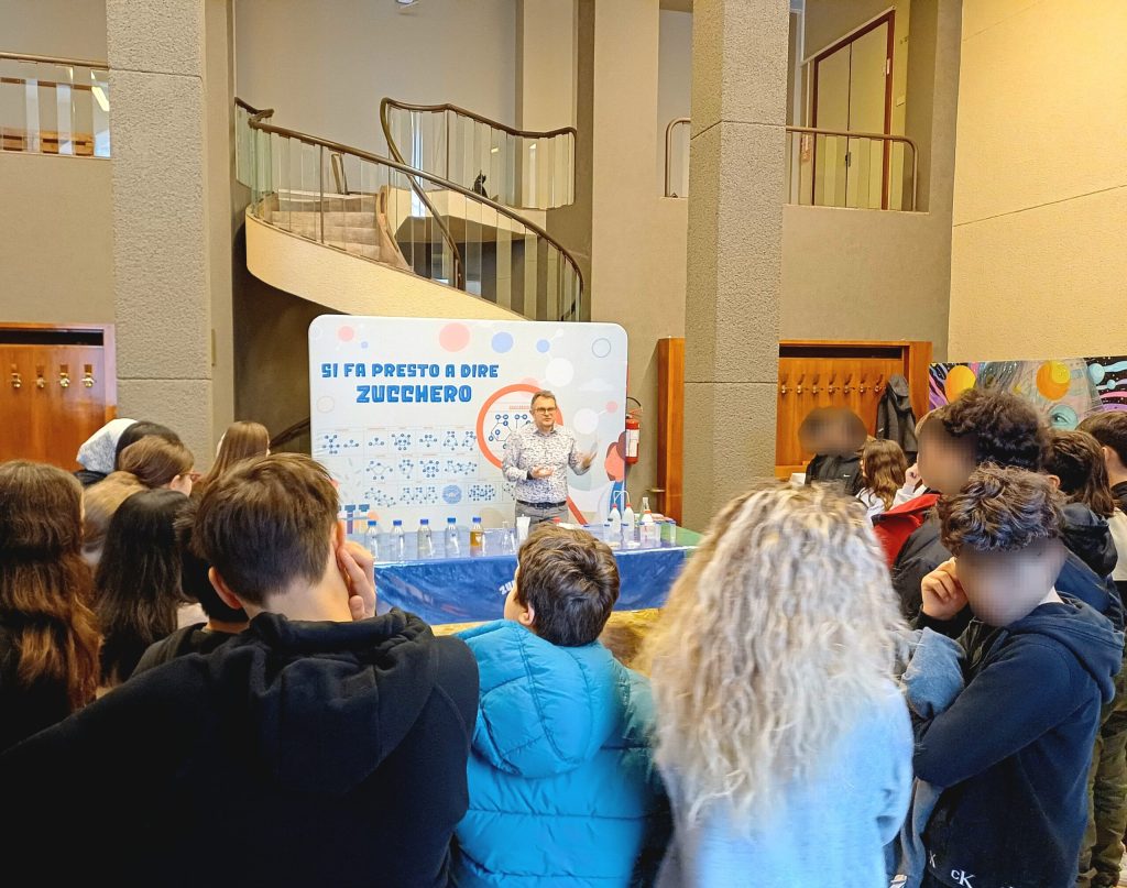 Bambini e adulti davanti al pannello di Zucchero & Co. nell'atrio del CICAP Fest di Padova