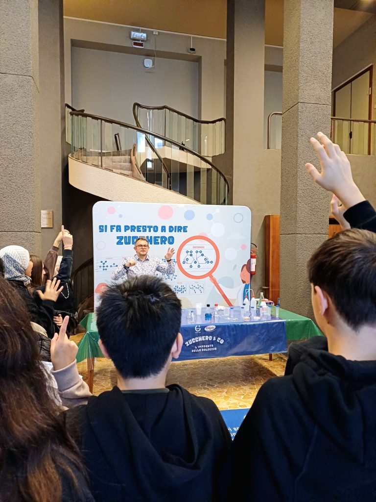 Un ragazzo alza la mano davanti al pannello del laboratorio sullo zucchero