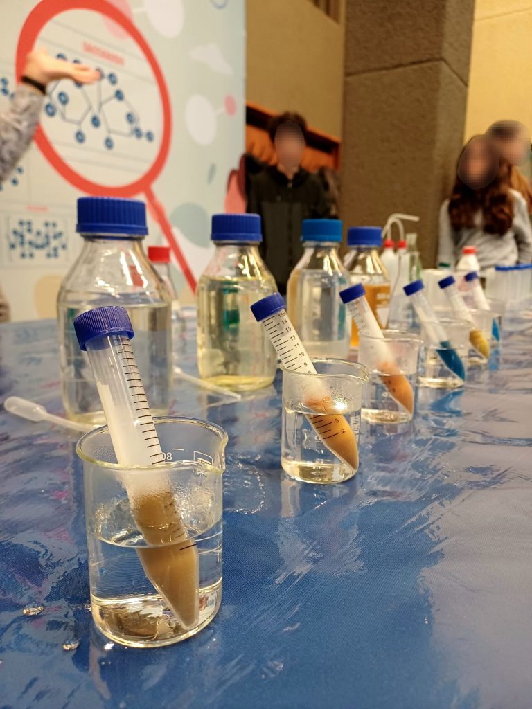Provette con lo zucchero in primo piano, davanti al pannello del laboratorio