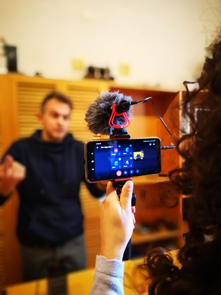 Due divulgatori si riprendono con lo smartphone nella sala del museo