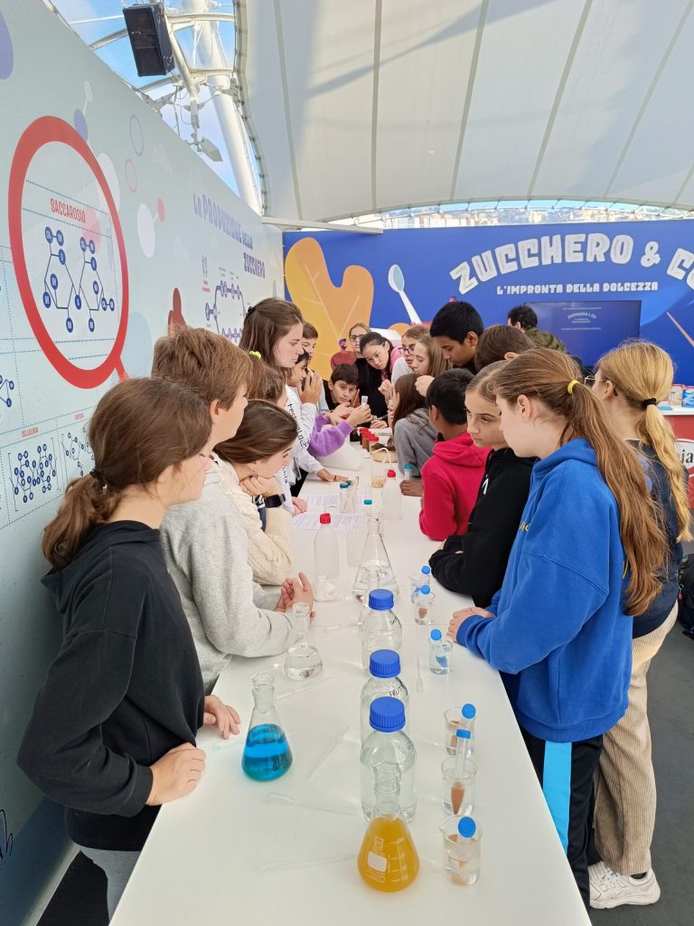 Studenti al tavolo degli esperimenti dell'allestimento Zucchero & Co.