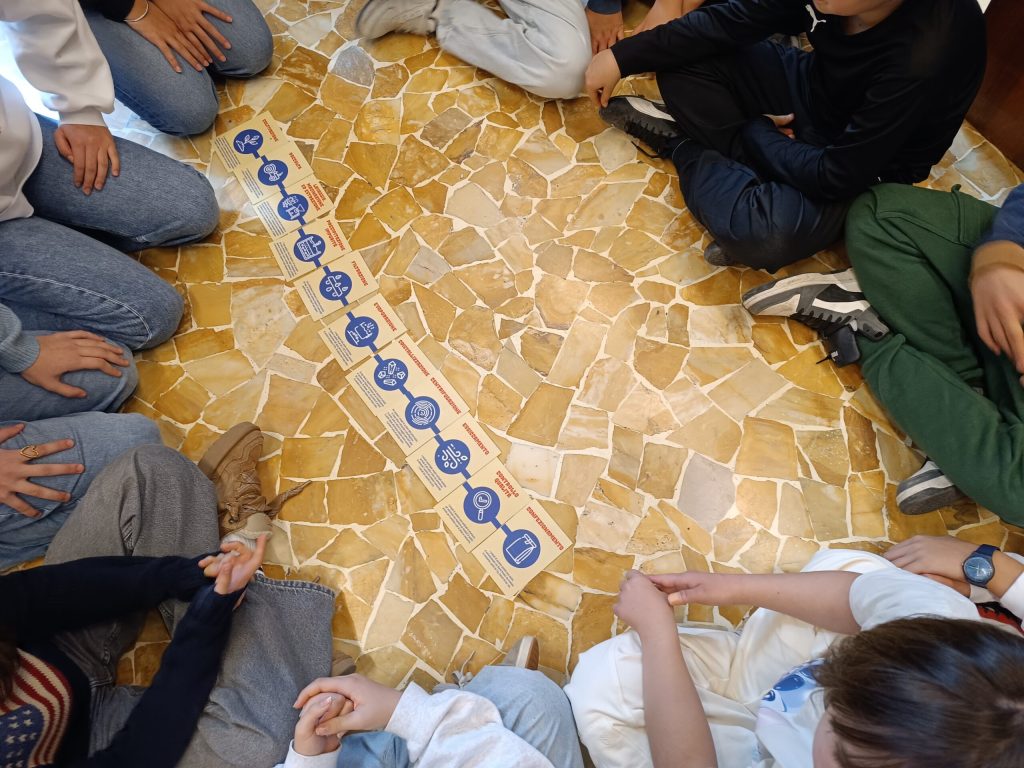 Partecipanti seduti a terra in cerchio intorno alla catena illustrata delle molecole